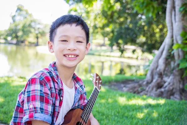 Menino jogando ukulele no parque — Fotografia de Stock