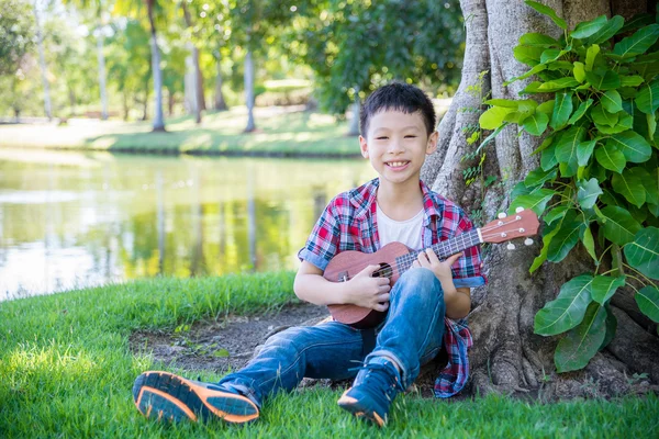 Menino jogando ukulele no parque — Fotografia de Stock
