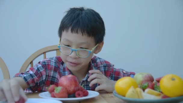 Niño comiendo frutas frescas en casa — Vídeos de Stock