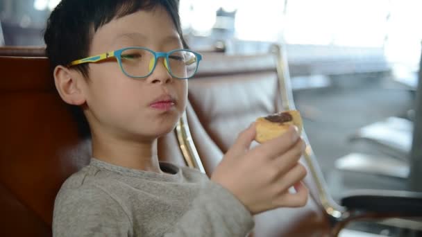 空港でパイを食べるアジア少年 — ストック動画