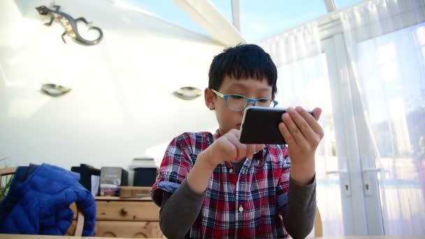 Хлопчик грає в ігри на телефоні — стокове відео