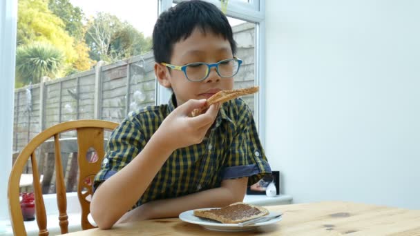 Niño comiendo tostadas en casa — Vídeo de stock