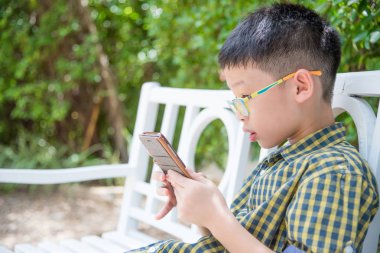 Genç Asyalı çocuk akıllı telefonda oyun oynamak