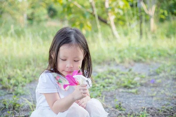 Девушка нюхает цветок в саду — стоковое фото
