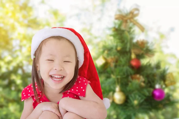 Meisje in KERSTMUTS glimlachend voor de kerstboom — Stockfoto