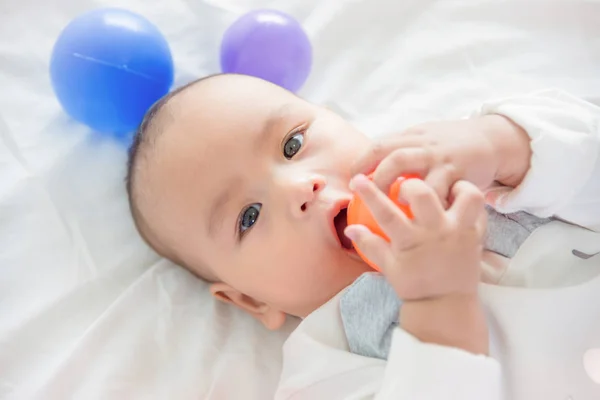 Little child lying on bed with ball — Stock Photo, Image