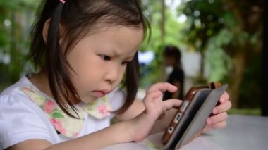 Akıllı telefon yolu ile çizgi film izlerken küçük Asyalı kız 