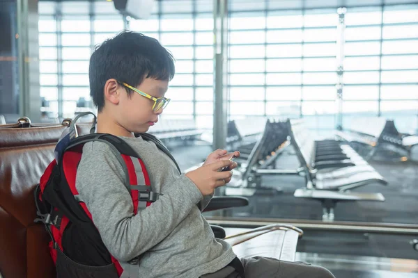 boy playing games on smart phone in airport