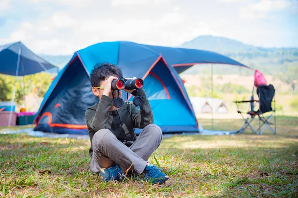 Chico mirando a través de binocular en camping —  Fotos de Stock