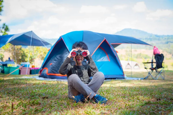 Chico mirando a través de binocular en camping —  Fotos de Stock