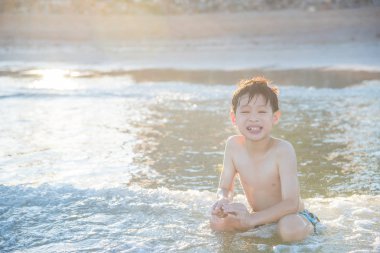 Genç Asyalı çocuk kumsalda oynarken
