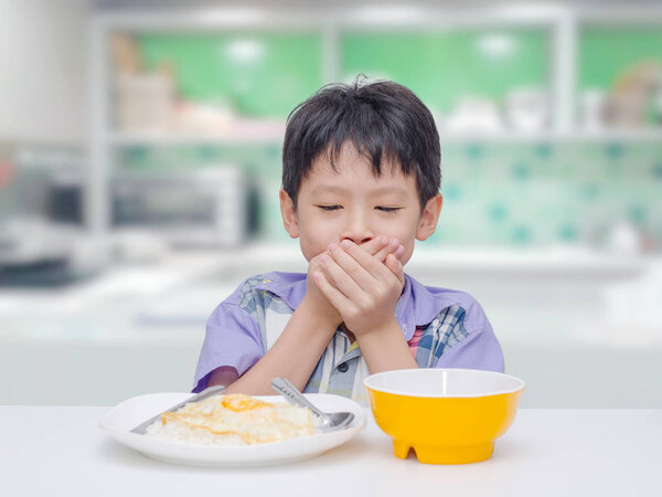 Asian child close his mouth by hand between having lunch
