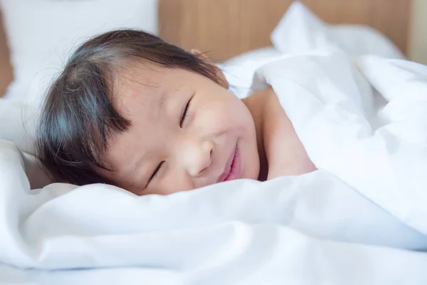 Meisje glimlachend in deken op bed — Stockfoto