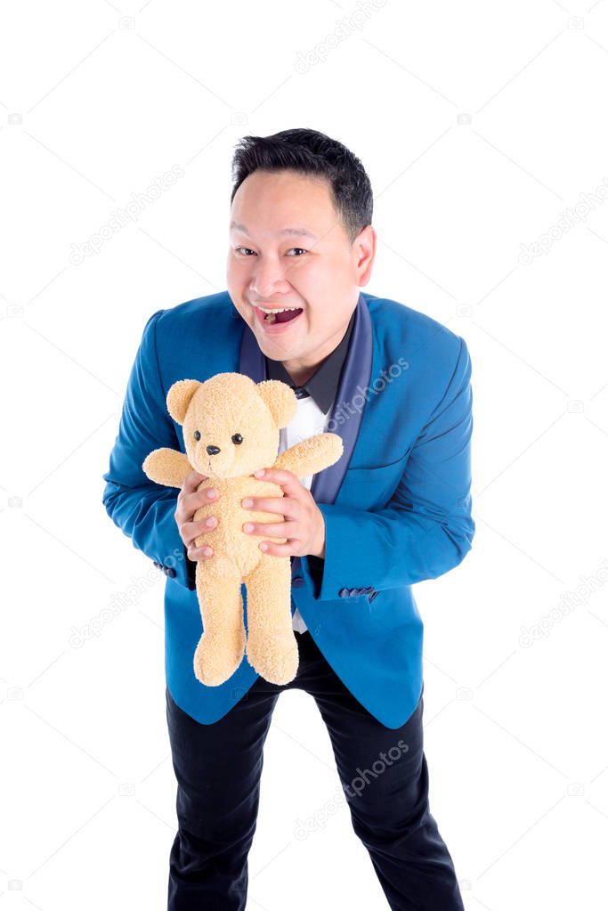 Asian man in blue suit holding teddy bear and smiles over white