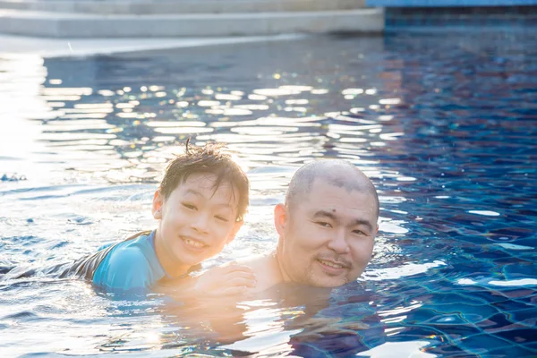 father and son swimming in pool