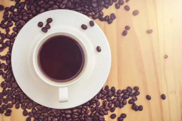 Xícara de café com grãos na mesa — Fotografia de Stock