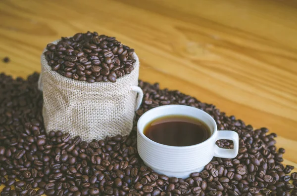 Xícara de café com grãos na mesa — Fotografia de Stock