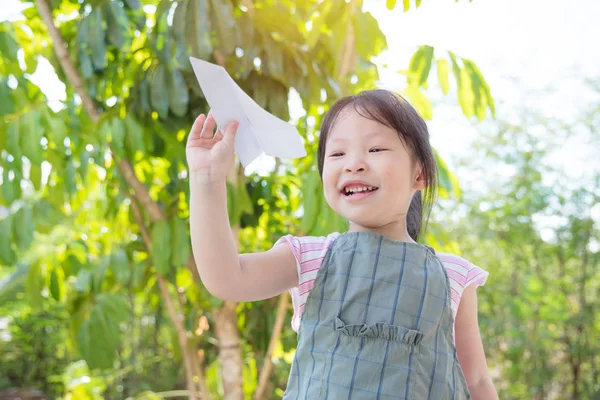 Meisje spelen papieren vliegtuigje in park — Stockfoto