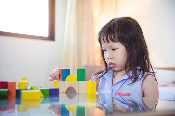 Menina jogando bloco de madeira em casa — Fotografia de Stock