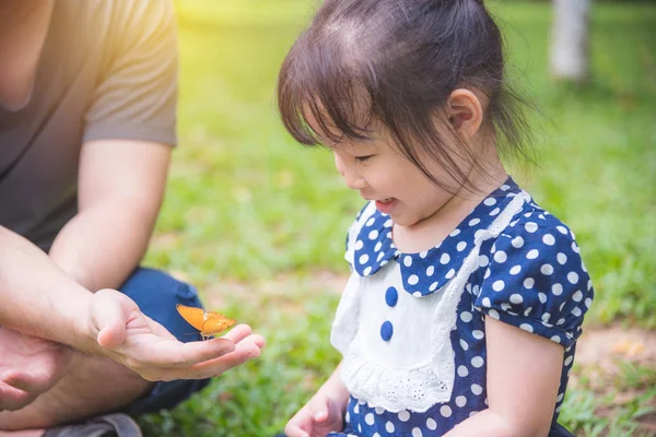 Little asian girl looking at butterflies in park — Stock Photo, Image
