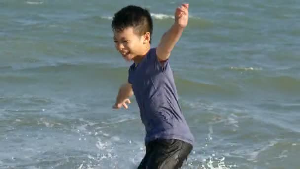 Chlapec v příboji na pláži v létě — Stock video
