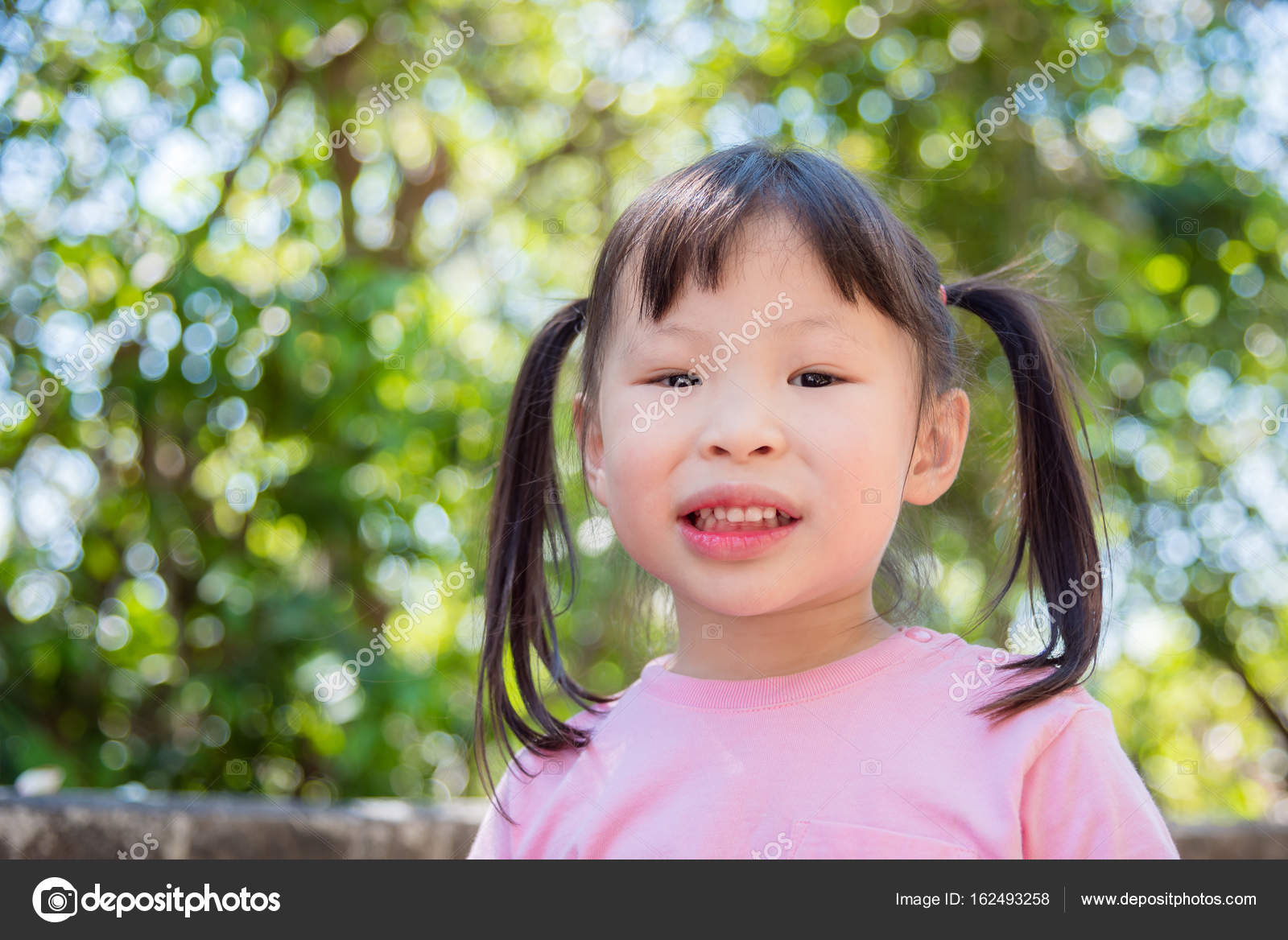 Little girl smiling while standing in backyard Stock Photo by ...