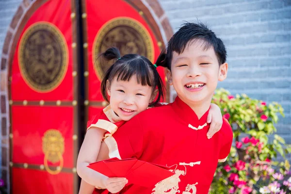 Happysiblings no traje tradicional chinês que prende o dinheiro vermelho do pacote — Fotografia de Stock