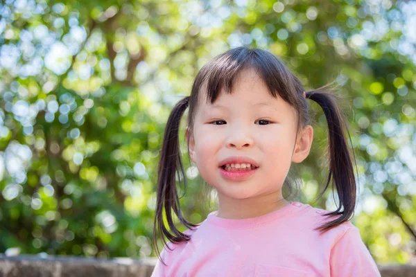 Küçük kız bahçede duran gülümseyen — Stok fotoğraf