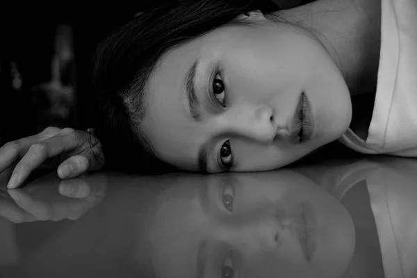 Sad woman lying on table with reflection — Stock Photo, Image