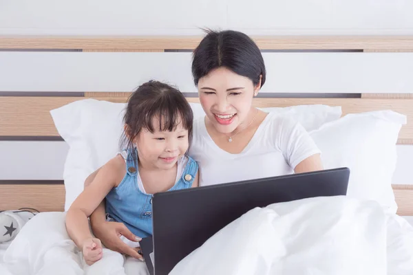 Anne ve kızı yatağa dizüstü bilgisayar kullanan — Stok fotoğraf