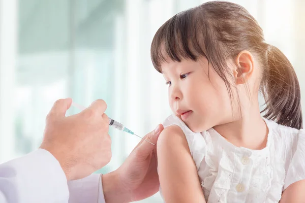 Lille pige, der modtager vaccination fra læge - Stock-foto