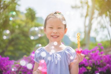 parkta bubles üfleme sırasında gülümseyen kız