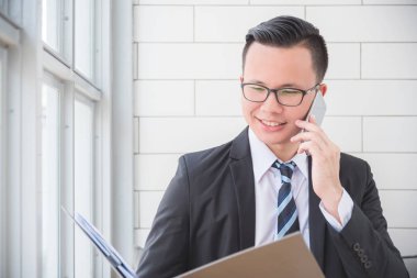 ofiste cep telefonu kullanırken gülümseyen iş adamı