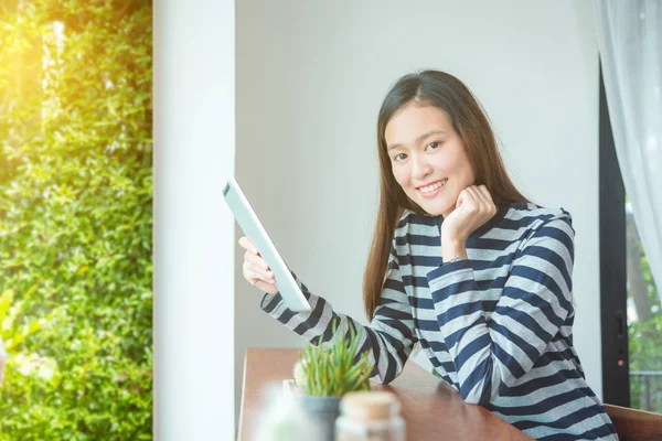 Junge Frau lächelt, während sie Tablet-Computer benutzt — Stockfoto