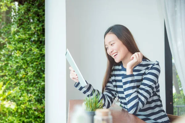 Junge Frau lächelt, während sie Tablet-Computer benutzt — Stockfoto