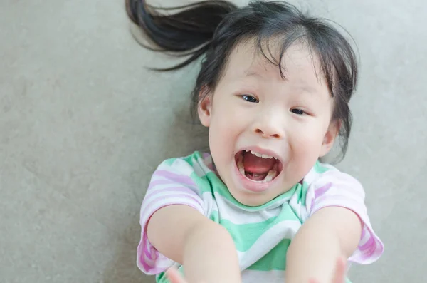 Bambina sorride sdraiata sul pavimento — Foto Stock