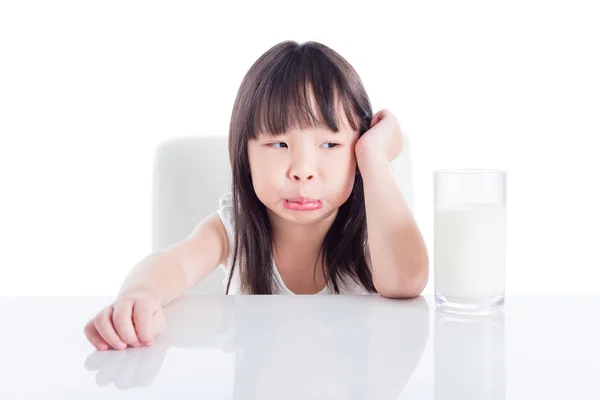 Ragazza con la faccia infelice guardando un bicchiere di latte — Foto Stock