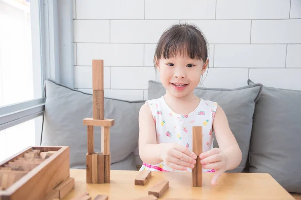 Niña sonriendo mientras juega bloques de madera en la mesa — Foto de Stock