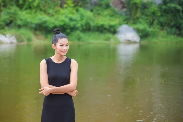 Κορίτσι με μαύρο φόρεμα χαμογελώντας κοντά στον ποταμό — Φωτογραφία Αρχείου