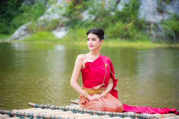 Mujer con vestido tradicional tailandés sentado en balsa de bambú — Foto de Stock