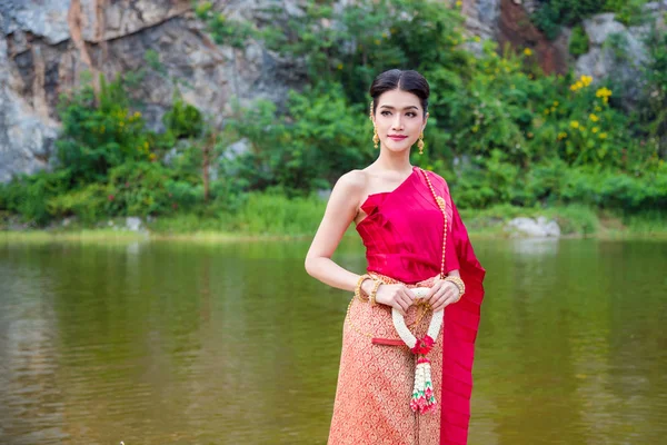 Frau in traditioneller thailändischer Kleidung mit Blumen in der Nähe des Flusses — Stockfoto