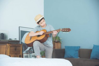 Çocuk evde oturma odasında gitar çalmak