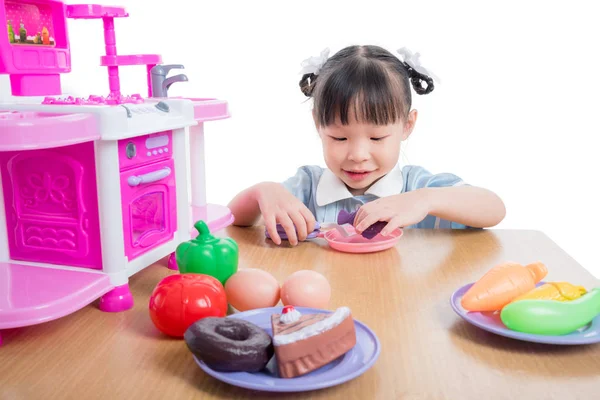 Küçük kız üzerinde beyaz mutfak oyuncakla oynamak 