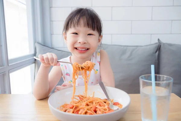 Ragazzina usando forchetta mangiare spaghetti da sola — Foto Stock