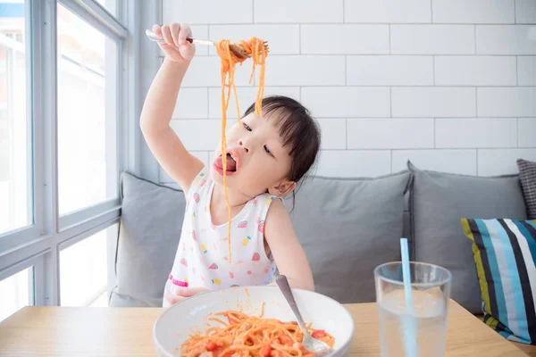 Ragazzina usando forchetta mangiare spaghetti da sola — Foto Stock
