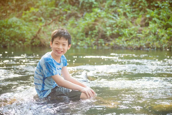 Boy smiling while palying in the river — Stock Photo, Image