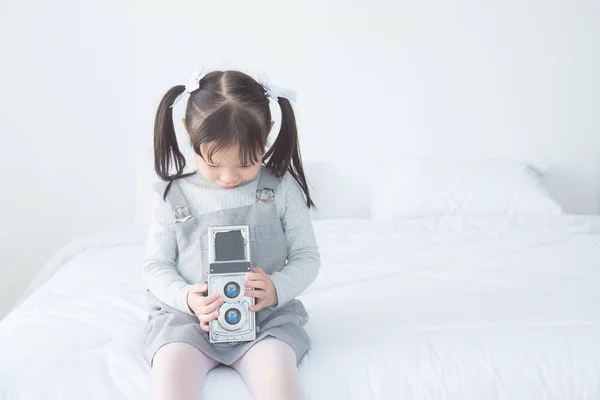 Meisje nemen foto door klassieke camera op bed thuis — Stockfoto