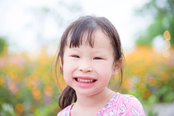 Girl smiling at camera in flower garden — Stock Photo, Image