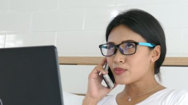 Not Defteri kullanarak ve evde cep telefonu ile konuşurken güzel Asyalı kadın 
