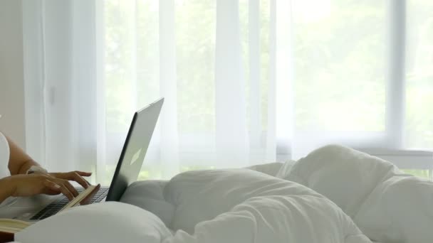 ベッドの上の美しいアジアの女性が彼女のラップトップを使用してウェブを閲覧するには — ストック動画